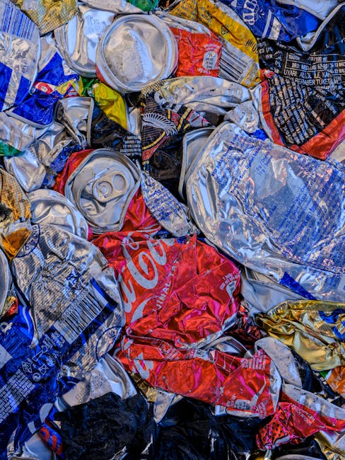 A large collection of overflowing waste and rubbish bags situated on a paved area next to a metal railing, with a silver car parked nearby in front of a commercial building. The rubbish includes black